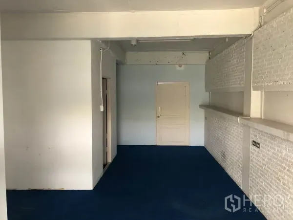 Office Space for rent in Ratchathewi, Bangkok - Open-plan office with blue carpet, white brick feature wall and a door at the back.