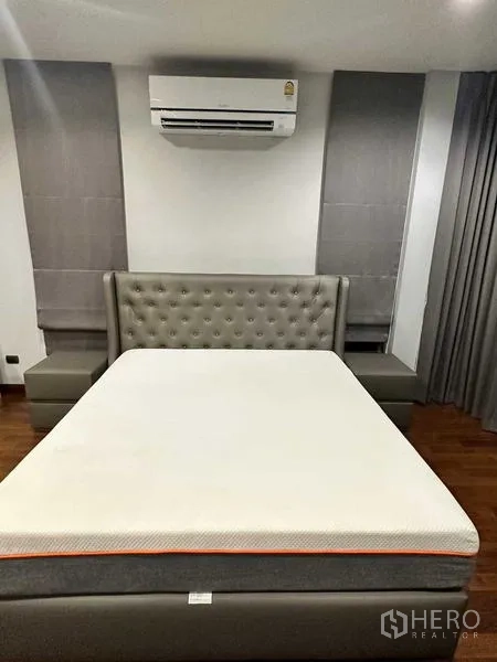 บ้าน ให้เช่าในLat Krabang, Bangkok - ห้องนอนเตียงหัวเตียงบุปุ่ม แอร์ ผ้าม่านสีเทา และพื้นไม้