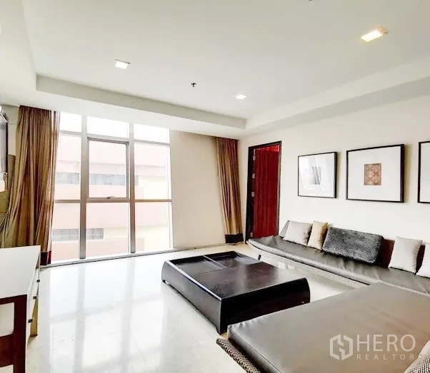 公寓 出租在Khlong Toei, Bangkok - 客厅采光充足，落地窗搭配长形沙发与矮茶几。