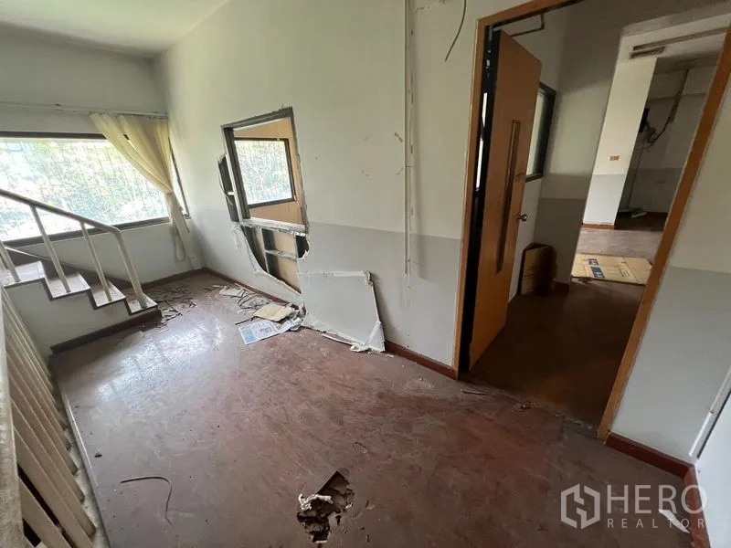 店屋 出租在Huai Khwang, Bangkok - 楼上一间带楼梯的房间，墙面破损，采光良好。