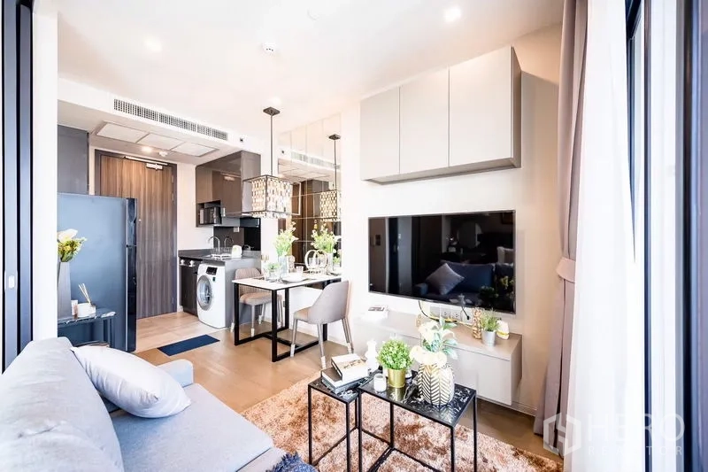 Condominium for rent in Watthana, Bangkok - Living–dining area with built-in kitchen, washing machine and pendant lighting.