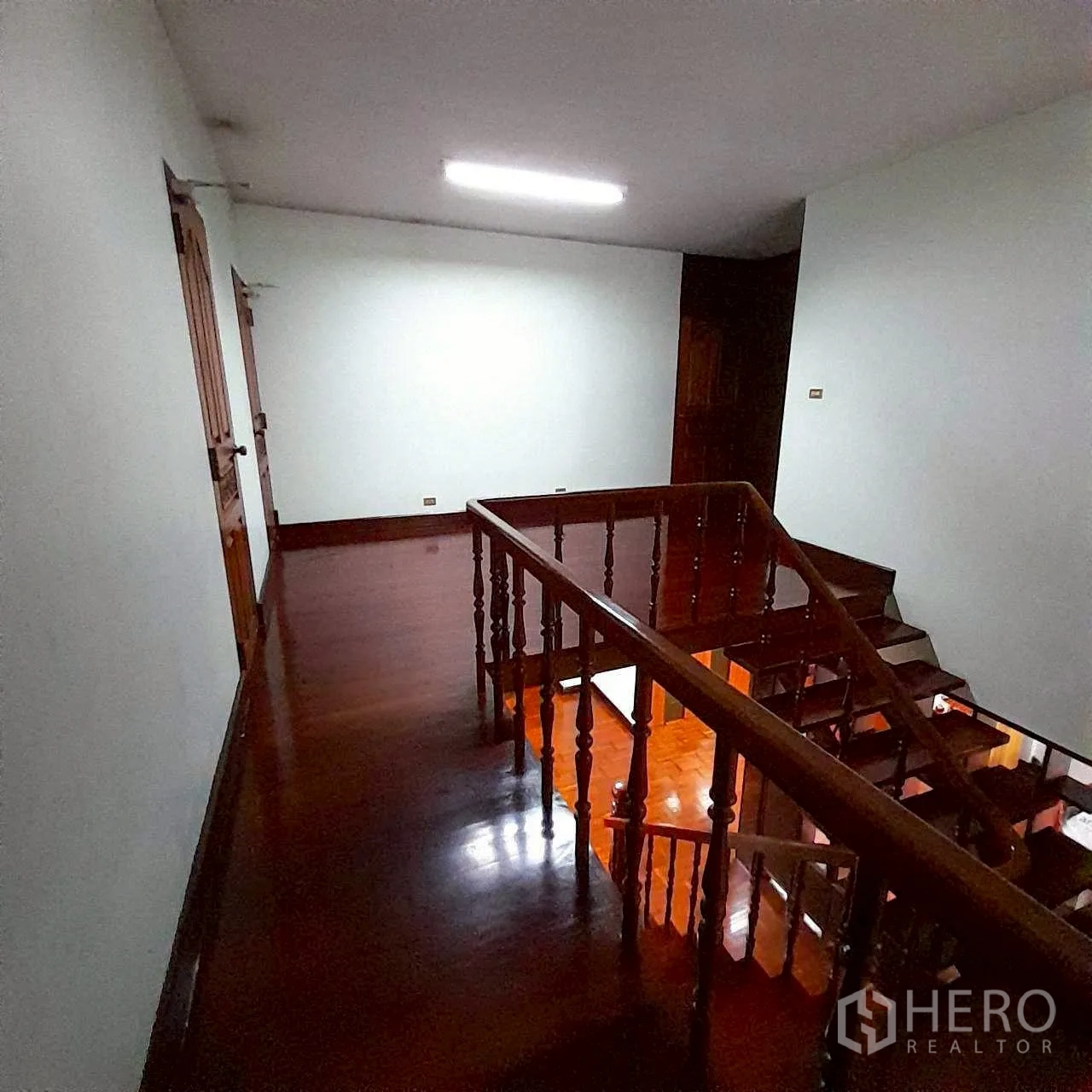 Home Office for rent in Bang Rak, Bangkok - Staircase and hallway with glossy timber floors and white walls.