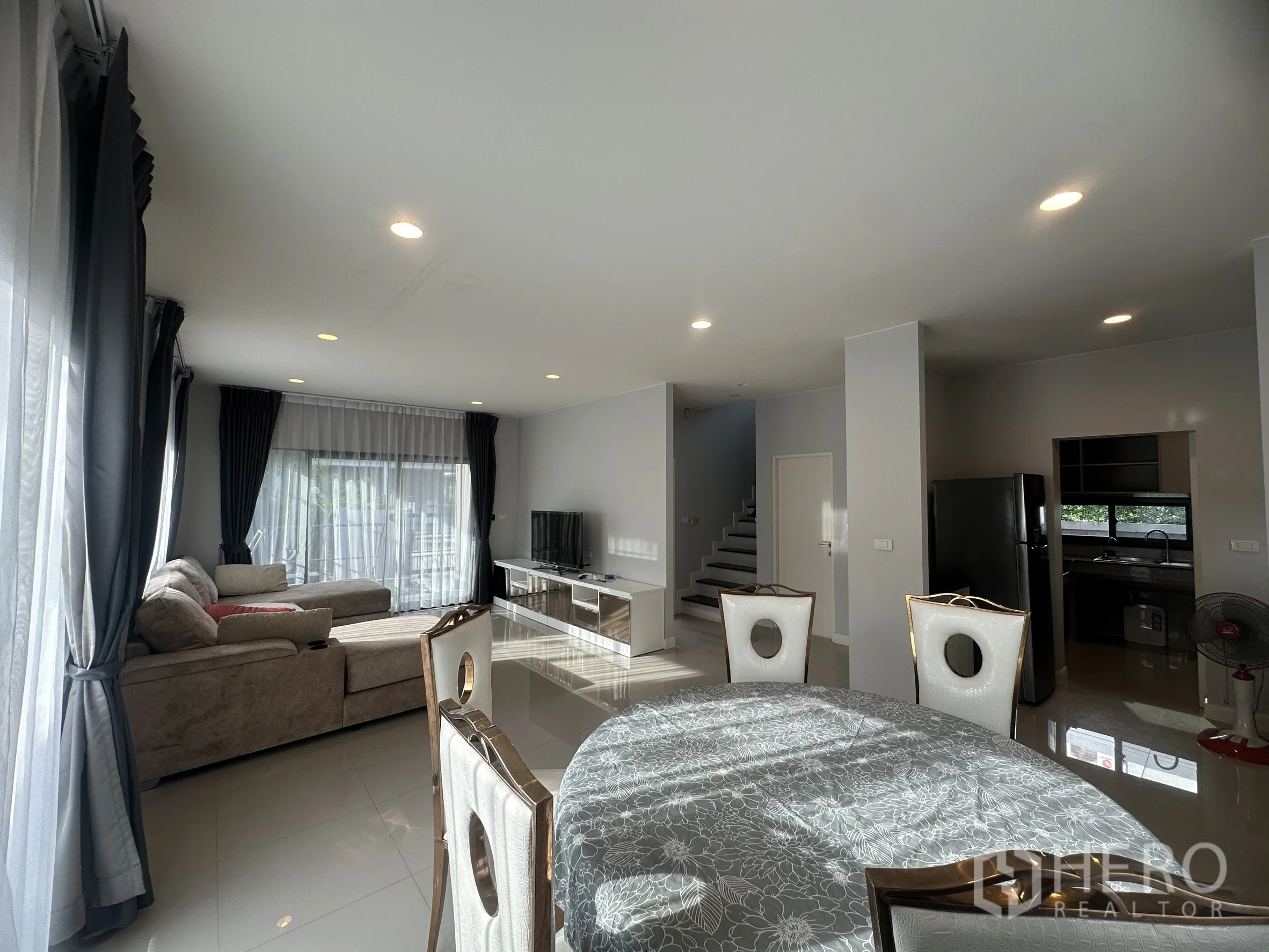 独栋房屋 for rent or sale in Lam Luk Ka, Pathum Thani - 开放式客餐厅，配沙发、电视柜并与厨房相连。