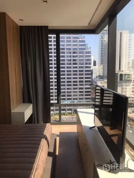 公寓 出租在Bang Rak, Bangkok - 卧室一角设电视柜，通高玻璃尽览都市天际线。
