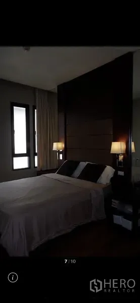 Condominium for rent in Watthana, Bangkok - Master bedroom showing dark wood feature wall, bedside sconces and a neatly made queen bed.