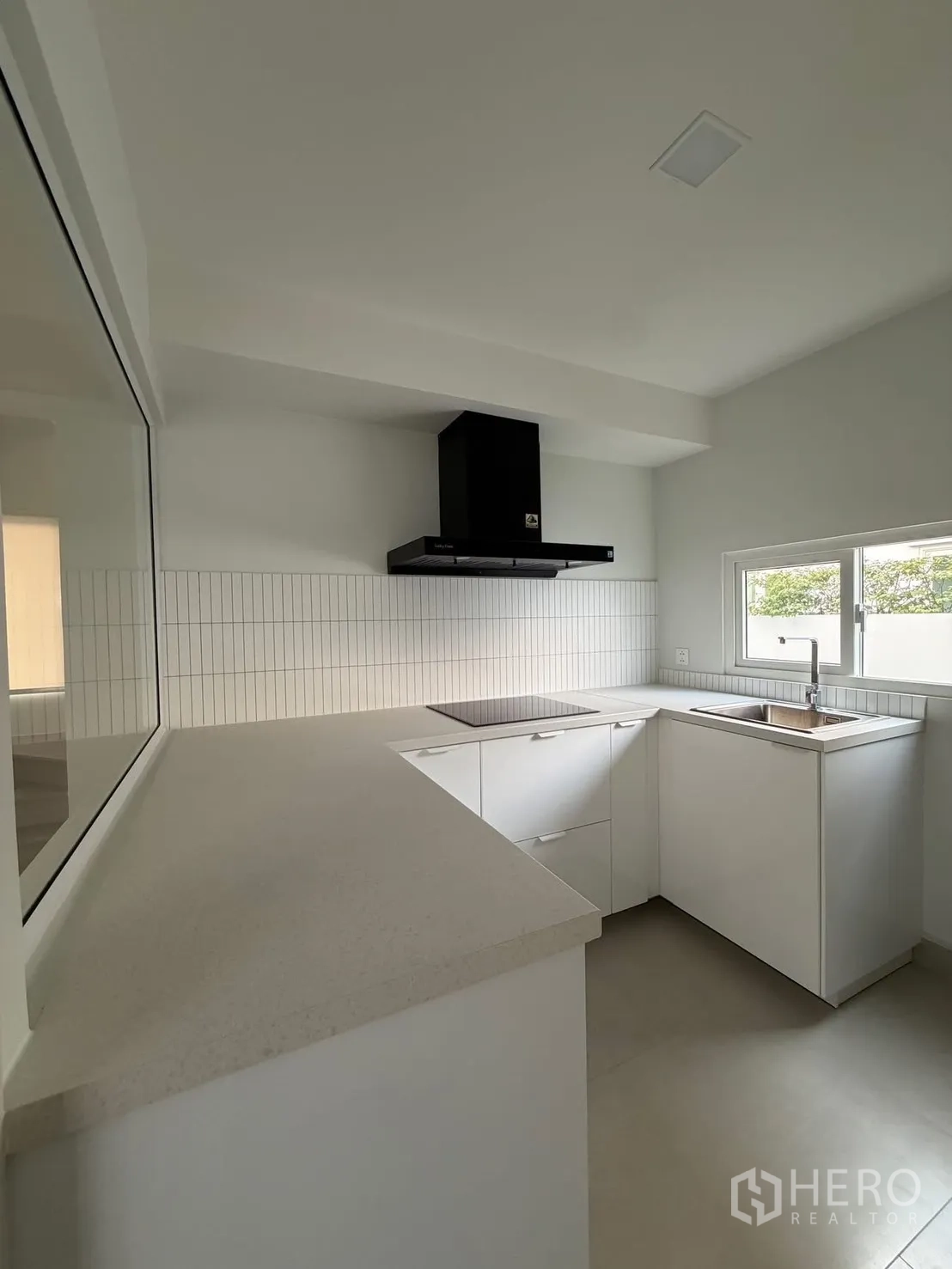 บ้าน ให้เช่าในBang Na, Bangkok - ครัวรูปตัวแอลสว่าง ตู้สีขาว เคาน์เตอร์หิน หน้าต่าง และเครื่องดูดควันสีดำ