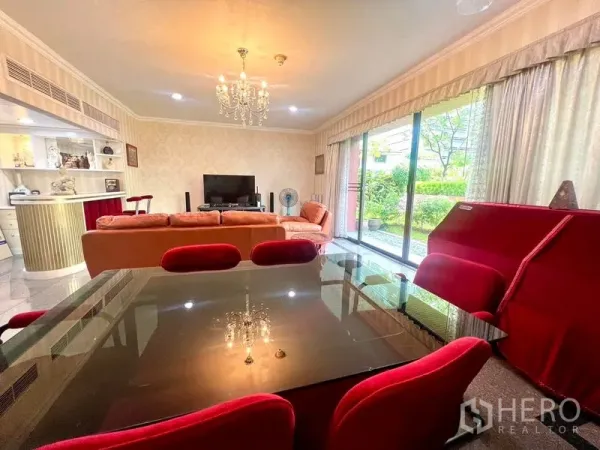 คอนโด ขายในPathum Wan, Bangkok - ห้องนั่งเล่นและรับประทานอาหารกว้าง แชนเดอเลียร์ เก้าอี้สีแดง และประตูกระจกสไลด์เปิดสู่เทอเรซสวน