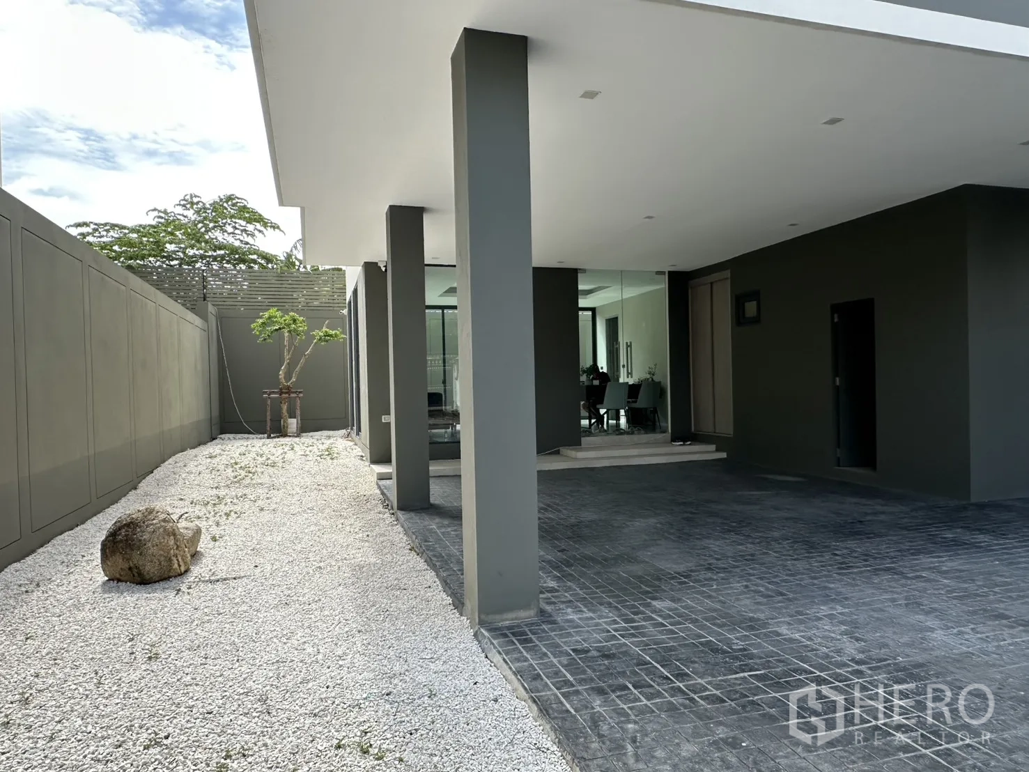 Home Office for rent or sale in Suan Luang, Bangkok - Side walkway with white gravel landscaping and columns leading to glass lobby.