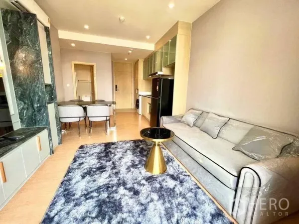 คอนโด ให้เช่าหรือขายในWatthana, Bangkok - ห้องนั่งเล่นสว่าง โซฟา พรมฟู และชุดโต๊ะทานข้าวติดกับครัวแบบเปิด