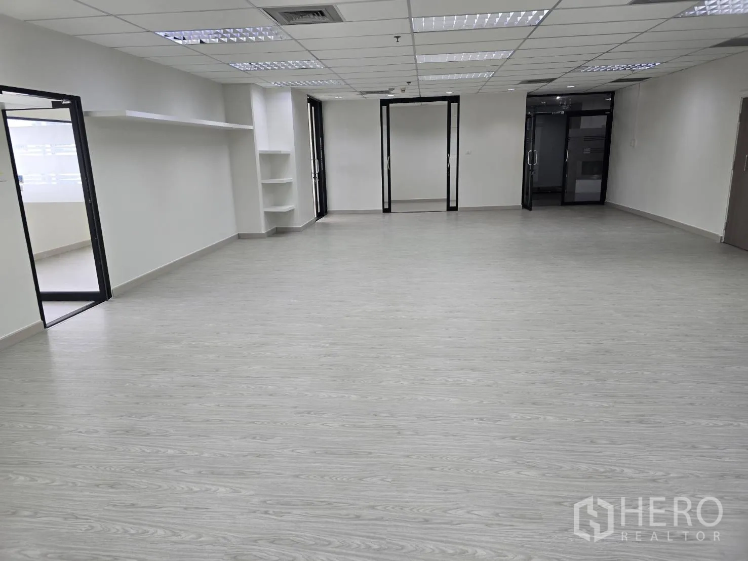 Office Space for rent in Khlong Toei, Bangkok - Large open-plan office with light wood flooring, white walls, and glass doors to side rooms.