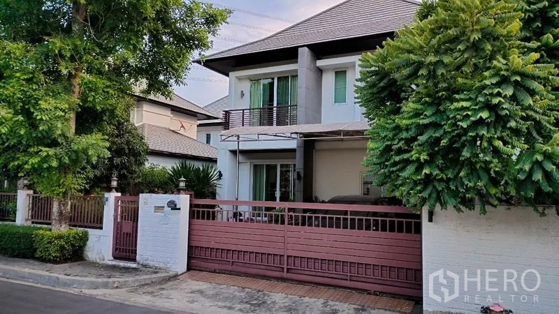 独立式住宅 出租在Prawet, Bangkok - 两层独栋别墅外观，滑动大门、车棚与绿树