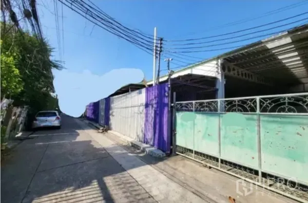 Warehouse for rent in Din Daeng, Bangkok - Gated warehouse frontage on a narrow lane with overhead power lines, suitable for small pickups.