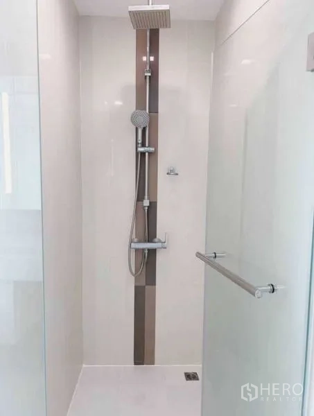 Condominium for rent in Watthana, Bangkok - Living room with sofa, TV and sliding doors to a balcony with city views.