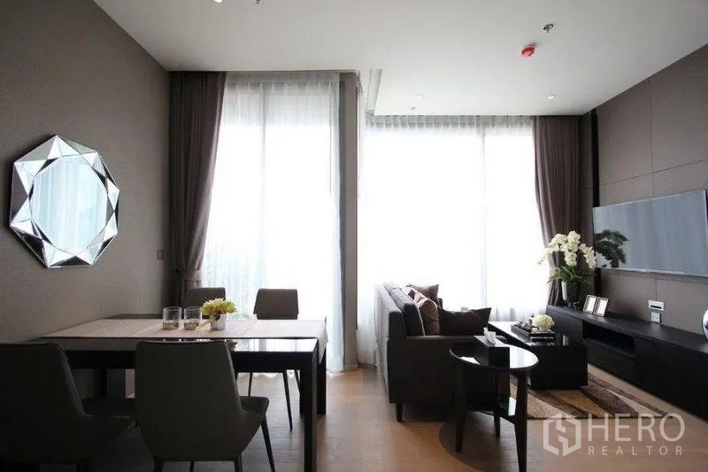 Condominium for rent in Watthana, Bangkok - Spacious living and dining zone with full-height windows and a TV media wall.