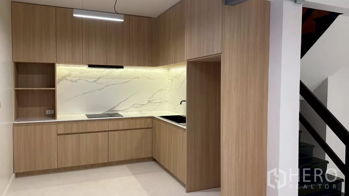Home Office for rent in Watthana, Bangkok - Built-in L-shaped pantry kitchen with wood cabinetry and marble-look backsplash.