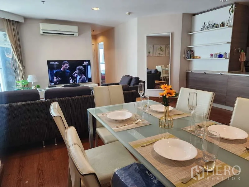Condominium for rent in Huai Khwang, Bangkok - Dining table set for six overlooking the lounge with TV and air-conditioning.