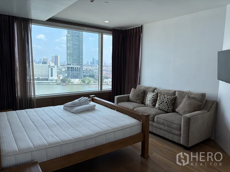 คอนโด for rent in Khlong San, Bangkok - ห้องนอนพร้อมหน้าต่างบานใหญ่เห็นวิวแม่น้ำ เตียงไม้ และโซฟานุ่ม