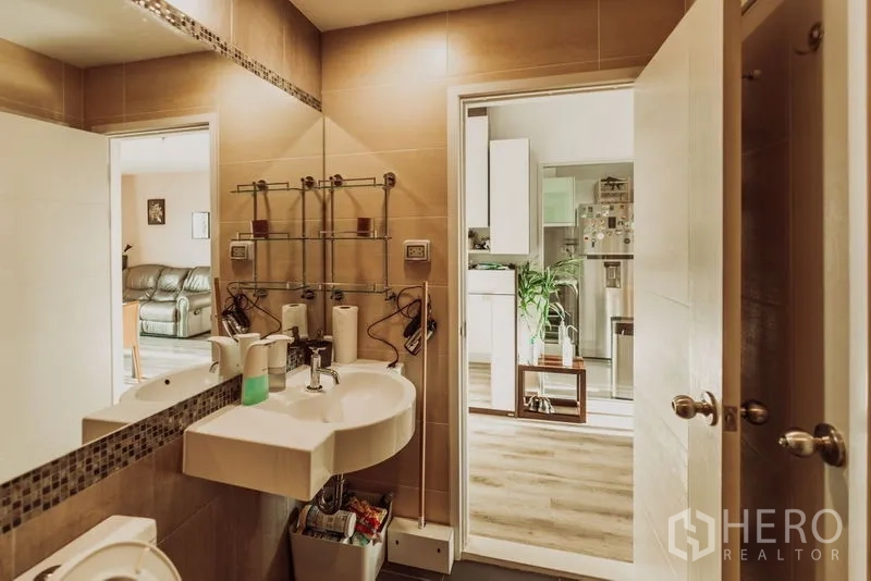 Condominium for rent in Sathon, Bangkok - Powder room with wide mirror and shelving, opening toward the living area.