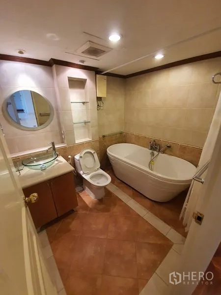 Condominium for rent in Pathum Wan, Bangkok - Tiled bathroom featuring a soaking bathtub, toilet, and vanity with glass basin.