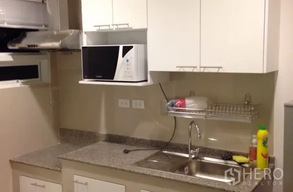 Detached House for rent in Saphan Sung, Bangkok - Modern kitchen with granite countertop, stainless sink, white cabinets and microwave