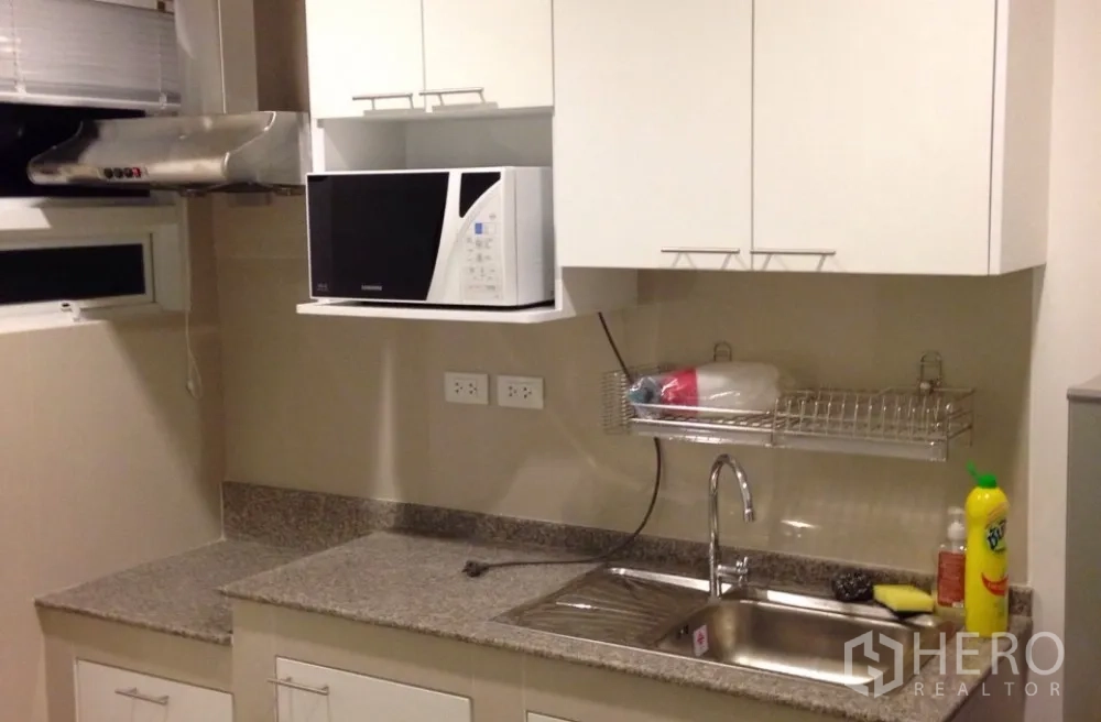 Detached House for rent in Saphan Sung, Bangkok - Modern kitchen with granite countertop, stainless sink, white cabinets and microwave