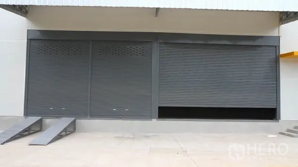 คลังสินค้า ให้เช่าในThung Khru, Bangkok - ประตูม้วนสีเทาหลายบานพร้อมทางลาดที่หน้าคลังสินค้า