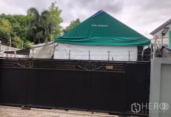 ที่ดิน ขายในPhra Khanong, Bangkok - ประตูรั้วเหล็กสีดำพร้อมลวดหนามกันรอบที่ดิน มีต้นไม้ด้านหลังรั้ว.