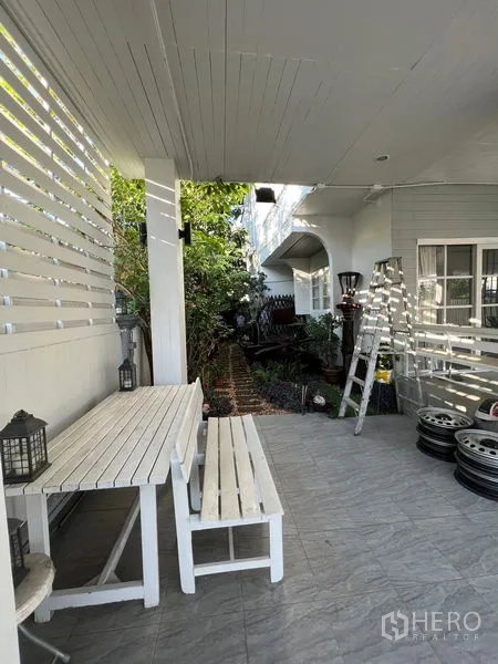 บ้าน ขายในLat Krabang, Bangkok - เฉลียงมีหลังคาพร้อมม้านั่งไม้สีขาวมองเห็นทางเดินสวน