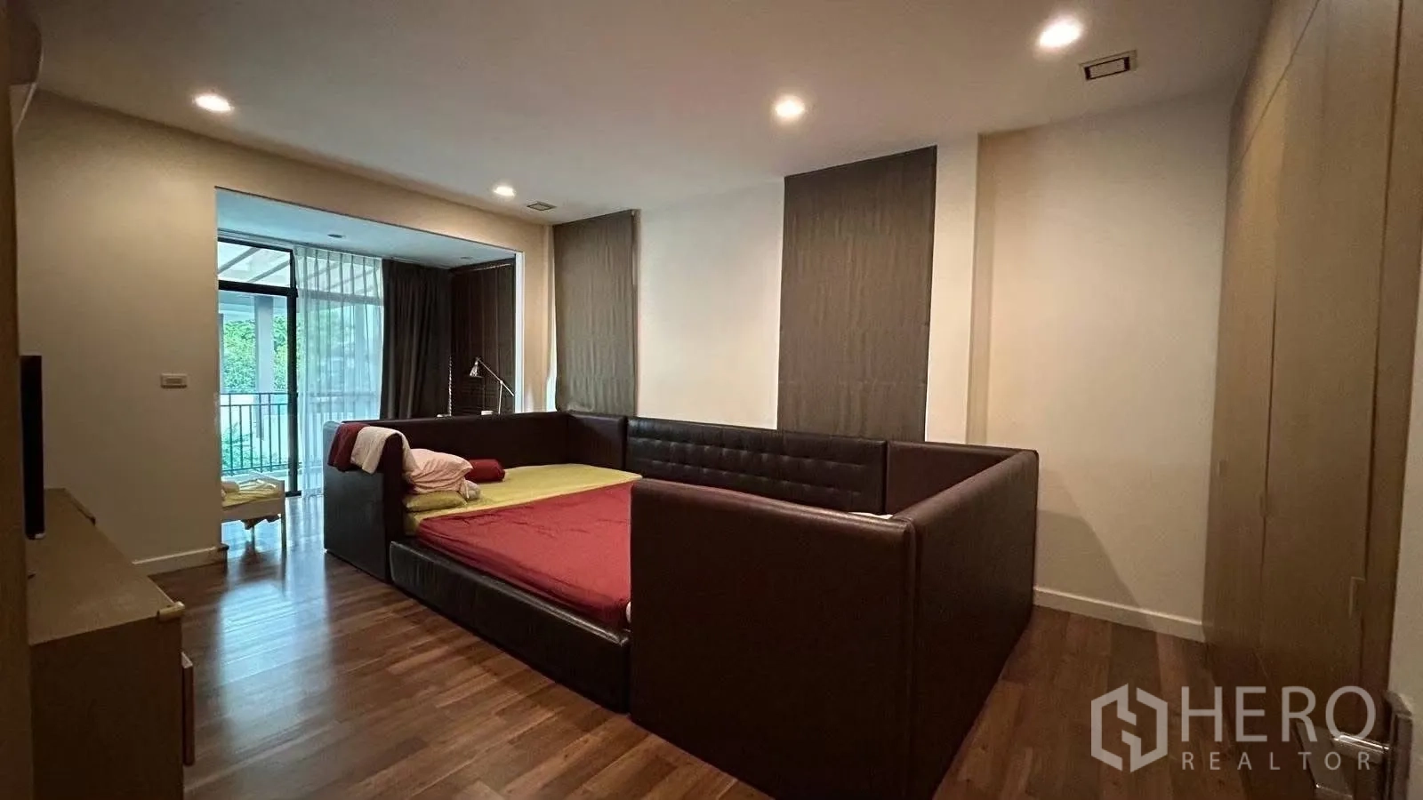 บ้านเดี่ยว for rent in Prawet, Bangkok - ห้องนอนใหญ่เตียงกรอบหนังสีเข้ม พร้อมทางออกสู่พื้นที่ระเบียงและมุมทำงาน
