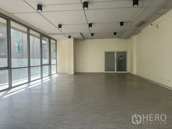 办公空间 出租在Phra Khanong, Bangkok - 宽敞办公室内景，整面窗墙、砖纹地板与双扇玻璃入口门。