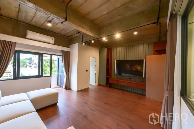 Home Office for rent or sale - Living lounge with sofa, TV wall, balcony access and wood flooring.