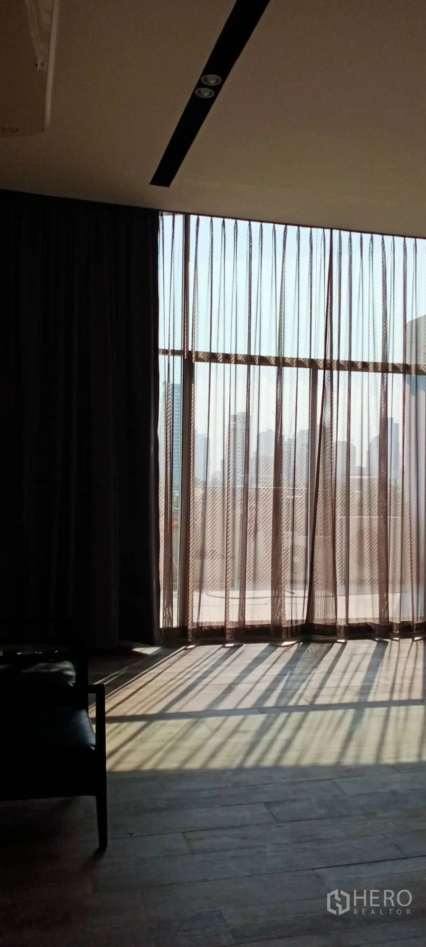 สำนักงาน ให้เช่า - มุมรับแขกของออฟฟิศ มองเห็นเส้นขอบฟ้าเมืองผ่านกระจกสูงและผ้าม่านทึบ-โปร่ง.