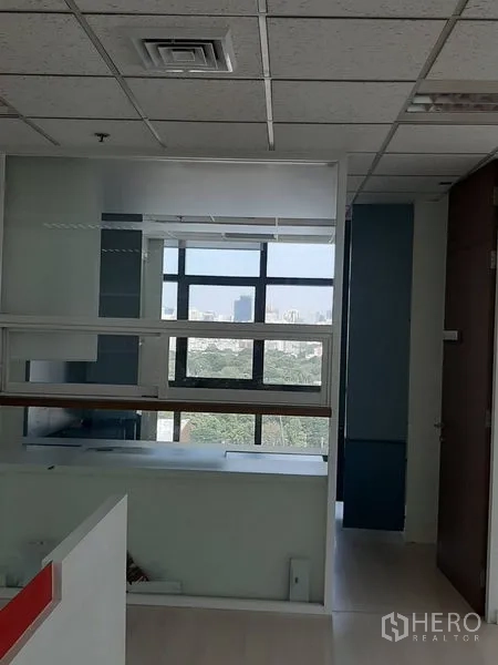 办公空间 出租在Bang Rak, Bangkok - 以玻璃隔间分隔的工作区，可见城市景观。