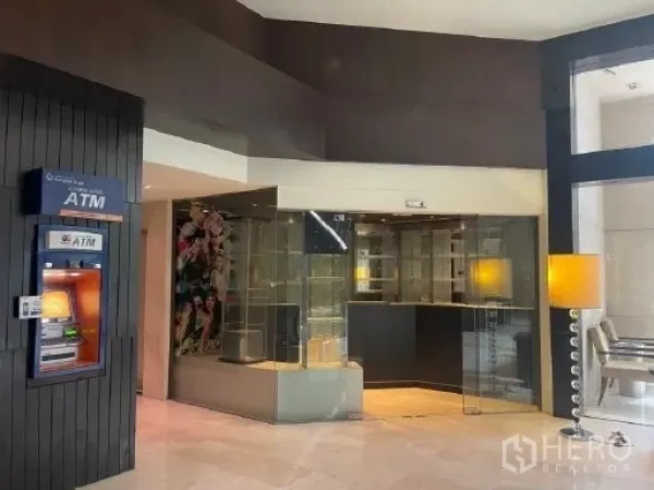 零售空间 出租在Watthana, Bangkok - 玻璃门店外观，面向明亮大楼大堂，旁有ATM与休息区。