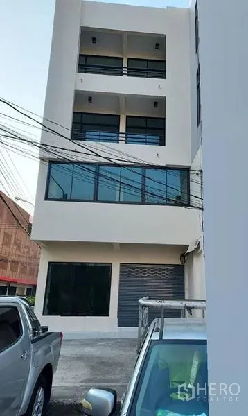 Shophouse for rent in Bang Kapi, Bangkok - Rear view of a multi-storey shophouse with roller shutter and parking area.