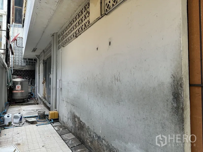 พื้นที่ขายของ for rent in Bang Rak, Bangkok - ทางเดินบริการแคบพื้นกระเบื้อง มีท่อและถังเก็บน้ำสแตนเลสข้างอาคาร