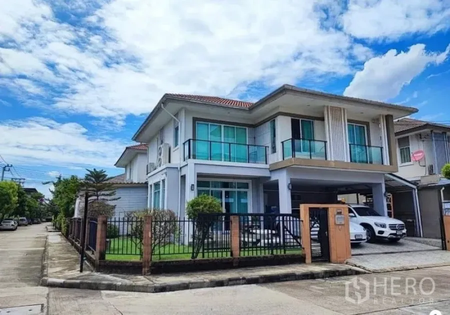Detached House for sale in Suan Luang, Bangkok - Street view of a modern two-storey house with glass balconies, driveway and carport.