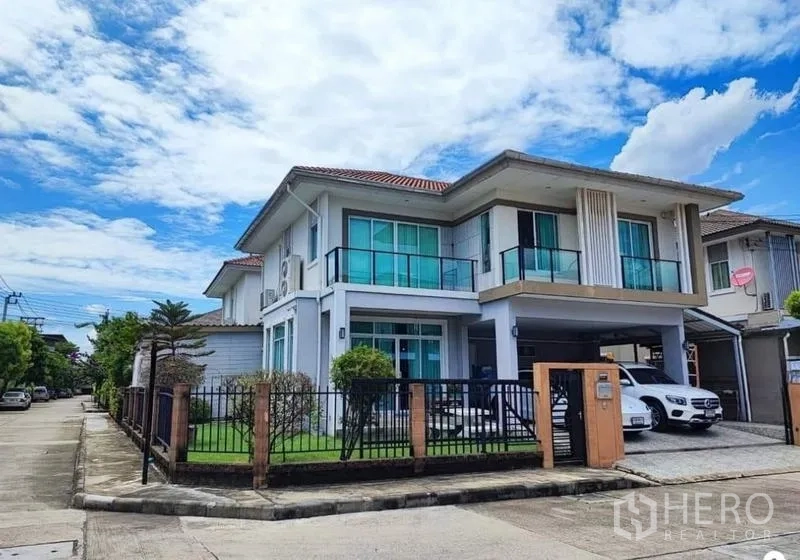 Detached House for sale in Suan Luang, Bangkok - Street view of a modern two-storey house with glass balconies, driveway and carport.
