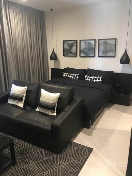 Condominium for rent or sale in Pathum Wan, Bangkok - Cozy bedroom with dark décor, pendant lamps, king bed and a sofa at the foot.