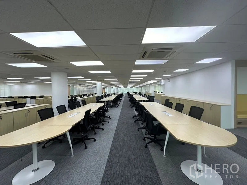 Office Space for rent - Wide corridor view of open-plan floor with central bench tables.