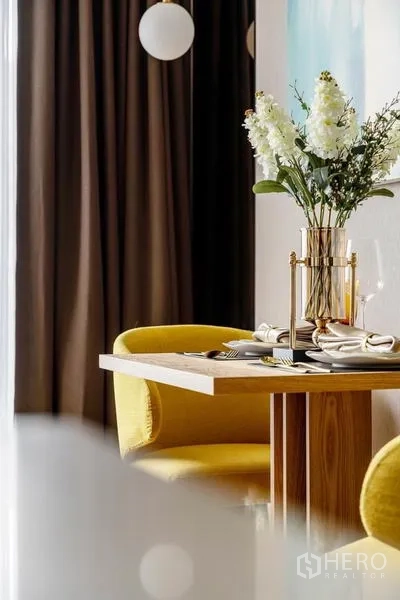 公寓 出租或出售在Bang Rak, Bangkok - 餐桌细节，鲜花、黄色餐椅与圆球吊灯。