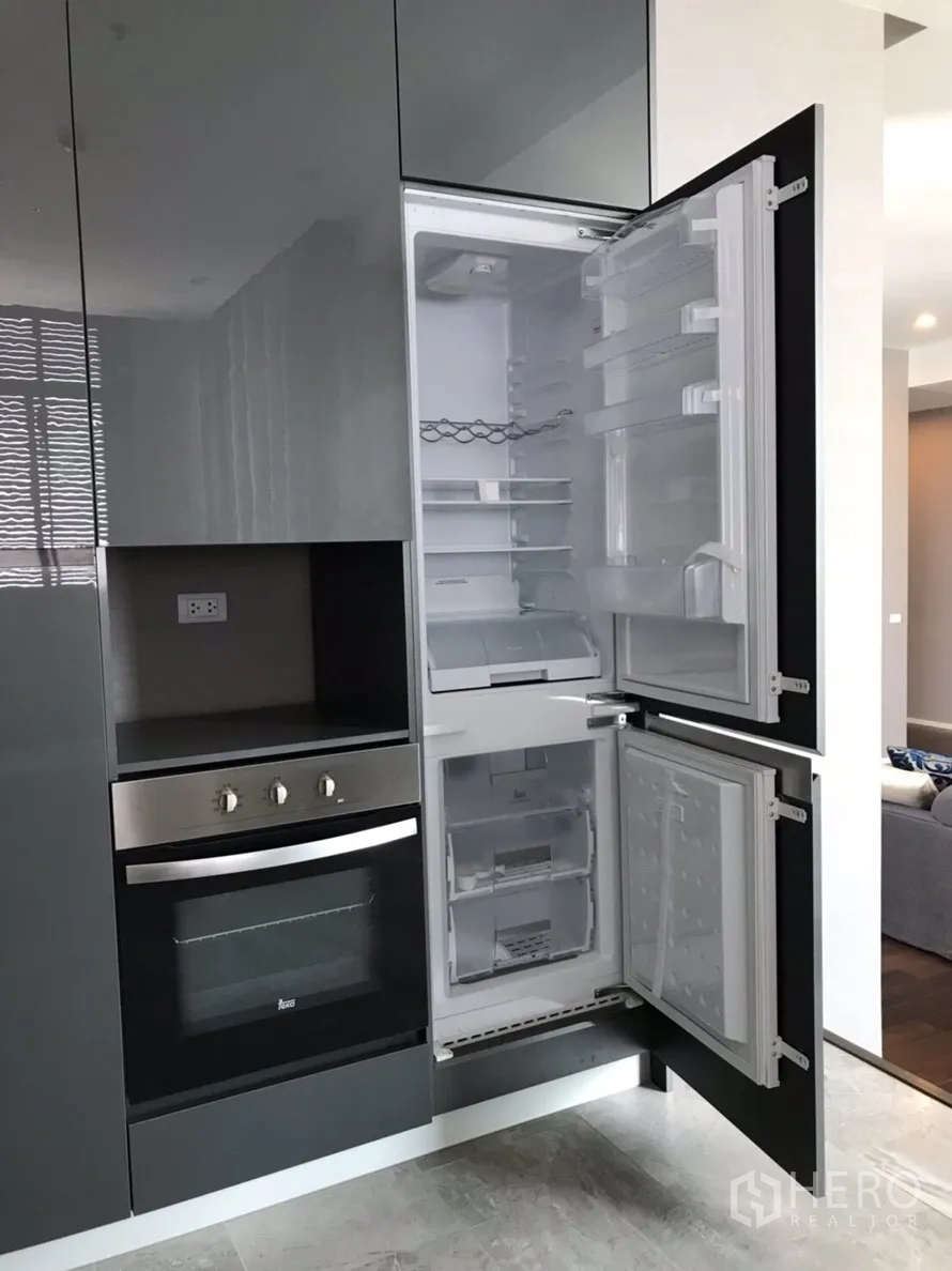 Condominium for rent or sale in Huai Khwang, Bangkok - Modern kitchen cabinetry with built-in oven and open integrated refrigerator.