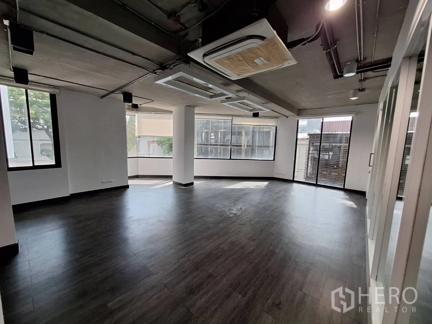 Office Space for rent - Spacious open-plan office with large windows, dark flooring and cassette air-conditioning.