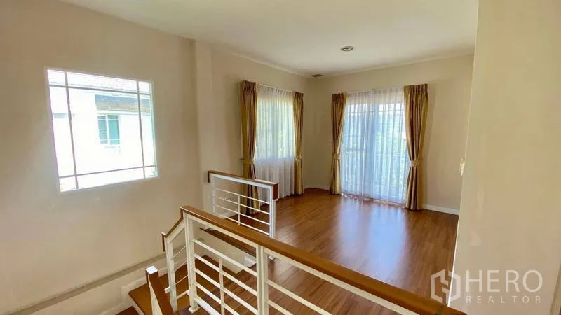 Detached House for rent in Bang Kapi, Bangkok - Second-floor family area beside staircase with balcony doors and curtains.