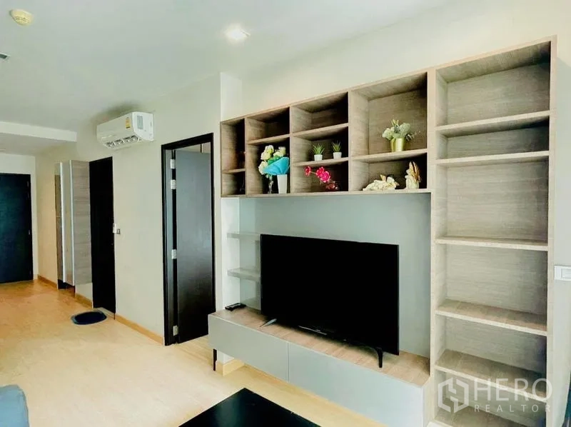 Condominium for rent - TV wall with built-in shelving and decorative plants in the living room.