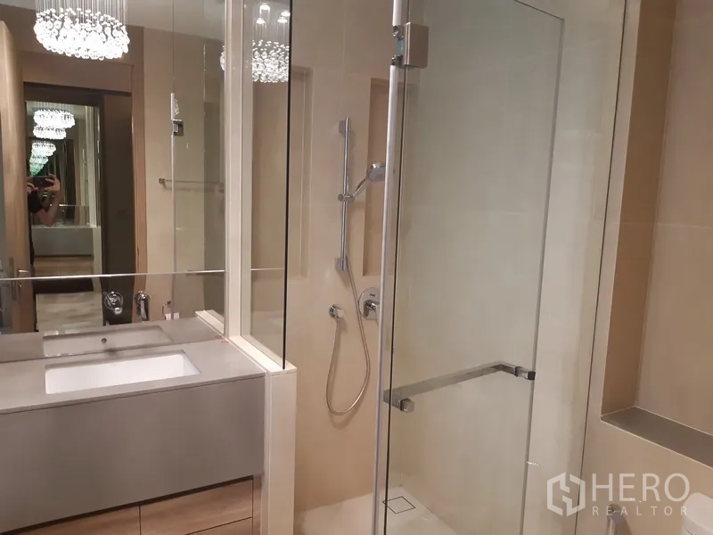 Condominium for rent or sale in Watthana, Bangkok - Contemporary bathroom with glass shower, vanity and mirror lighting beside a bathtub alcove.
