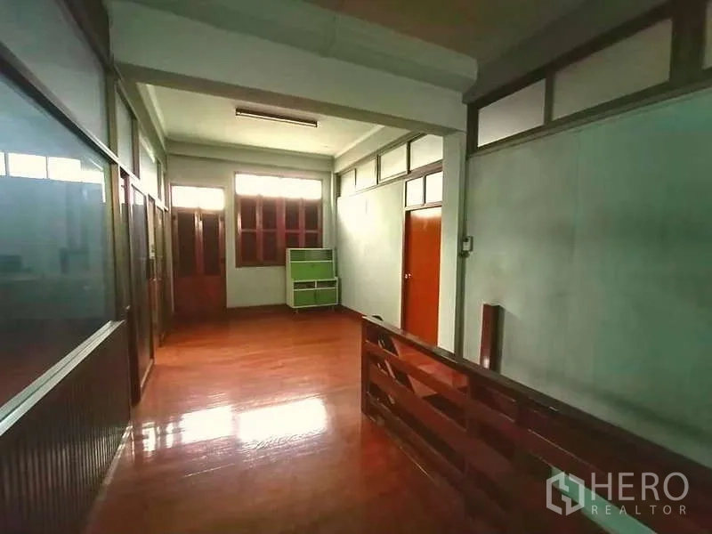 Shophouse for rent in Sathon, Bangkok - Landing and hallway with wooden handrail, glass partitions and polished floor leading to rooms.