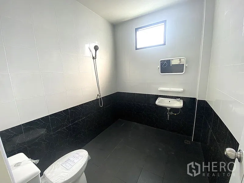 货栈 出租在Mueang Pathum Thani, Pathum Thani - 黑白配色卫浴，带花洒、马桶与壁挂式洗手盆。