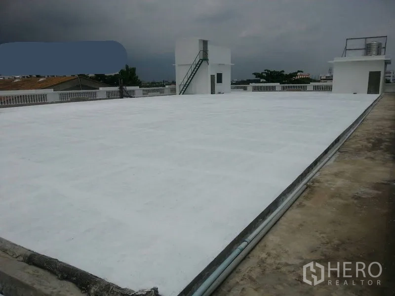 Office Space for rent - Expansive flat white rooftop with stair access and utility rooms under a cloudy sky.