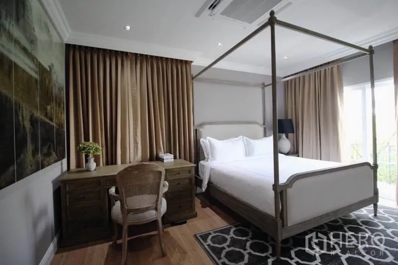 บ้าน ให้เช่าหรือขายในLat Phrao, Bangkok - ห้องนอนใหญ่เตียงสี่เสา พร้อมโต๊ะทำงาน พื้นไม้ และหน้าต่างกว้างติดผ้าม่าน